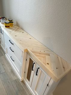 a kitchen counter made out of plywood and white cabinets with black handles on each drawer