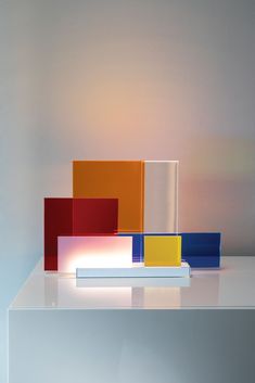 three different colored blocks sitting on top of a white table in front of a wall