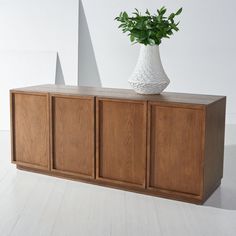 a white vase sitting on top of a wooden cabinet