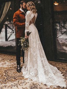 a bride and groom standing together in front of a window with snow on the ground