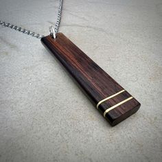 a wooden necklace with two gold strips on the end and a chain hanging from it