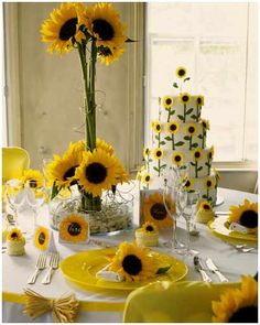 the table is set with sunflowers in vases, plates and napkins