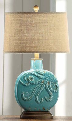 an octopus lamp on a table next to a light fixture with a beige linen shade