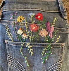 a pair of jeans with embroidered flowers in the back pocket