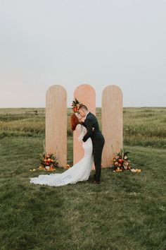 a bride and groom kissing in front of two large wooden letters with flowers on them