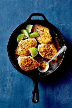 chicken with limes and spices in a cast iron skillet on a blue surface