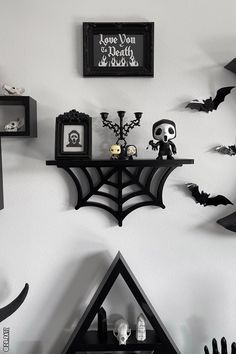 halloween decorations are displayed on the wall in this black and white photo, including a spider web shelf