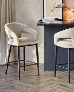 two white chairs sitting next to each other on top of a wooden floored floor