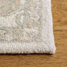 a white rug on top of a wooden floor with a wood flooring board in the background