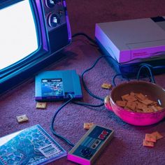 a bowl of crackers next to an old nintendo game console and other items on the floor