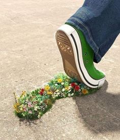 a person standing on top of a green shoe with flowers growing out of the bottom