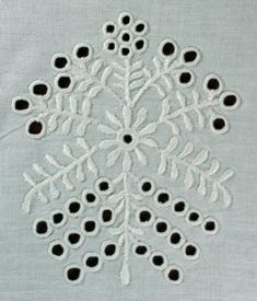 an embroidered snowflake is shown on a piece of cloth with holes in it