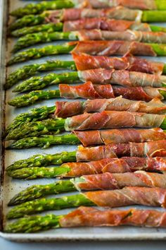 asparagus and prosciutto wrapped in bacon on a baking sheet ready to go into the oven