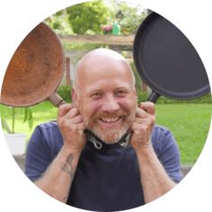 a man is holding two pans over his ears and smiling at the camera,