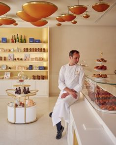 a man sitting at a counter in front of a display case filled with pastries