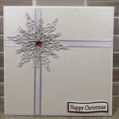 a white christmas card with a snowflake design on the front, and a red ribbon around it