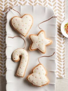 some cookies are on a white plate and one is shaped like a heart, the other has a star