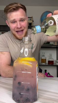 a man is pouring something into a glass bottle on a table with an orange and blue liquid in it