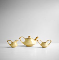 three yellow teapots sitting next to each other