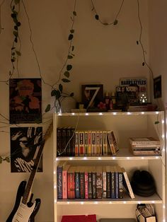 a bookshelf filled with lots of books next to a guitar