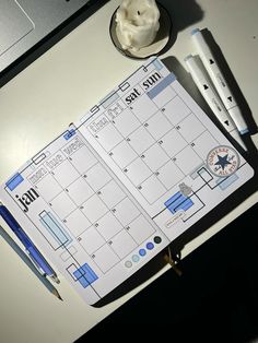 a desk with a calendar, pen and cup on it