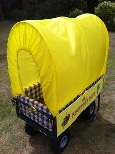 a yellow covered wagon sitting on top of a lush green field