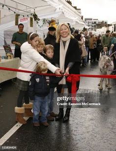 a woman and two children are cutting the ribbon