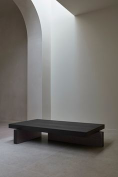 a black table sitting in the middle of a room next to a white wall and arched doorway