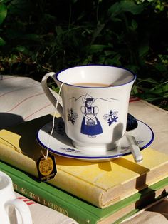 a coffee cup and saucer sitting on top of a stack of books next to each other