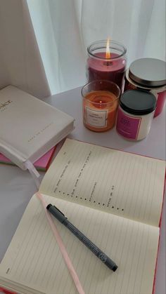 an open notebook sitting on top of a table next to a candle and some jars