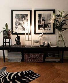 two pictures on the wall above a black table with zebra print rug and vases filled with flowers