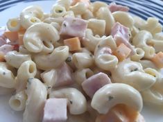 pasta salad with ham and cheese on a blue and white plate, ready to be eaten