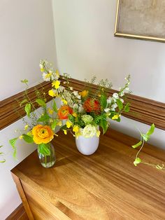 two vases filled with flowers on top of a wooden table