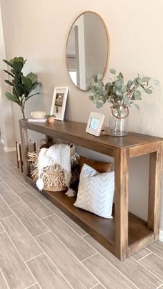 a wooden shelf with pillows and plants on it next to a mirror, planter and other items