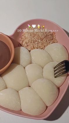 a heart shaped plate filled with dumplings, rice and dipping sauce on top of it