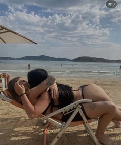 two women in bikinis are hugging on the beach