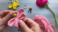 someone is crocheting a piece of pink yarn next to some flowers and beads