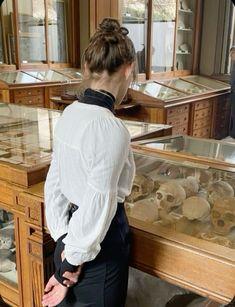 a woman standing in front of a display case filled with skulls