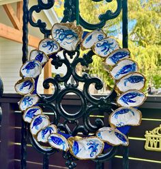 an ornate iron gate with blue and white dishes hanging from it's sides, in front of a house