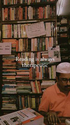 a man sitting in front of a book shelf filled with books