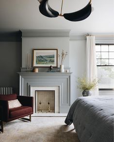 a bedroom with a fireplace, chair and painting on the wall next to the bed