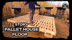 a man standing on top of a wooden pallet house floor in the middle of a field