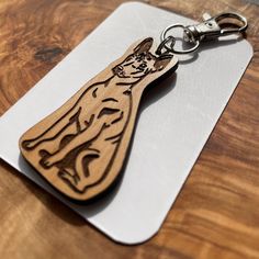 a wooden keychain with an image of a cat on it's side