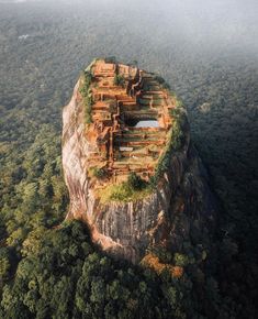 an aerial view of a building on top of a rock in the middle of trees