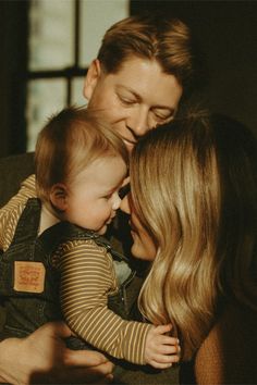 a man and woman holding a baby in their arms