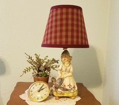 a lamp sitting on top of a table next to a clock and potted plant