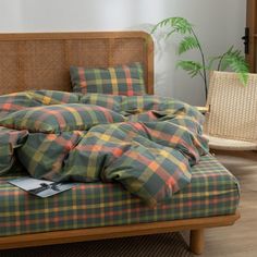 an unmade bed sitting on top of a wooden floor next to a potted plant