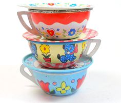 three bowls stacked on top of each other with flowers and hearts painted on the lids