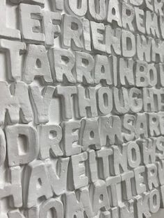 the words are written in many different languages on this white brick wall, which is covered with black and white letters