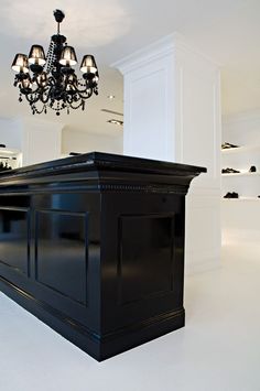 a chandelier hanging from the ceiling in a room with white walls and black furniture